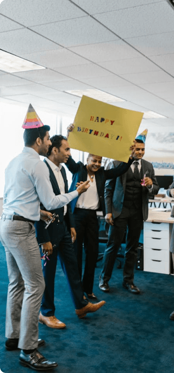 Coworkers celebrating a birthday in the office with a sign